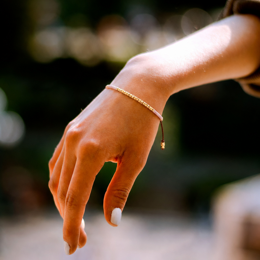 Close-up of a hand wearing a bracelet with a blurred natural background