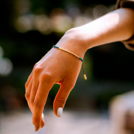 Close-up of a hand with a miyuki amozonite bracelet, blurred natural background